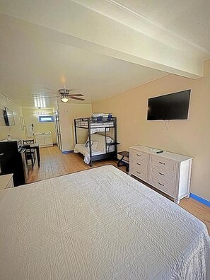 Un dormitorio con una cama litera, un televisor de pantalla plana, un escritorio y un aparador.