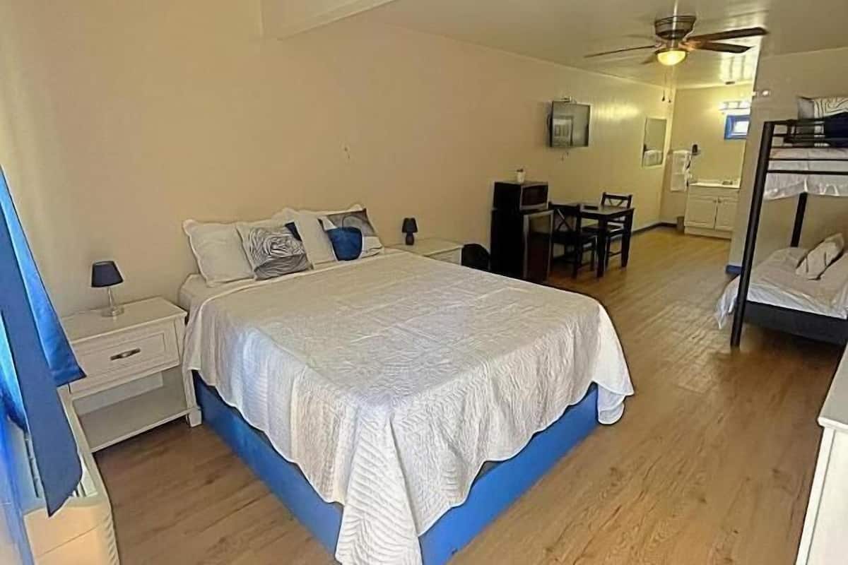 Un dormitorio con una cama, un escritorio, una silla, un ventilador de techo y una litera.