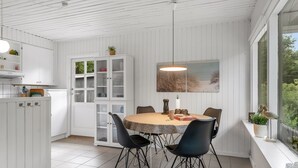 En matplats med ett runt bord, svarta stolar, en hängande lampa och ett fönster med utsikt.
