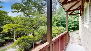 Un balcón de madera con vistas a un jardín y una casa.