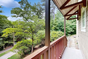 Ein Holzbalkon mit Blick auf einen Garten und ein Haus.