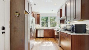 Una cocina moderna con gabinetes de madera, electrodomésticos de acero inoxidable y un ventanal que proporciona luz natural.