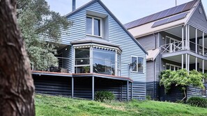 Ein zweistöckiges Haus mit Erkerfenster, einer Laube und Solaranlage auf dem Dach.