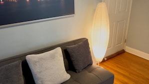 A grey sofa with two cushions, a floor lamp, and a framed picture on the wall. - Modern, cozy unit in quiet neighborhood close to EVERYTHING. (Coral Gables)