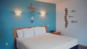 A bedroom with a bed, a nightstand, a wall-mounted sign, and a decorative wall piece. - Innlet Motel (Sturgeon Bay)
