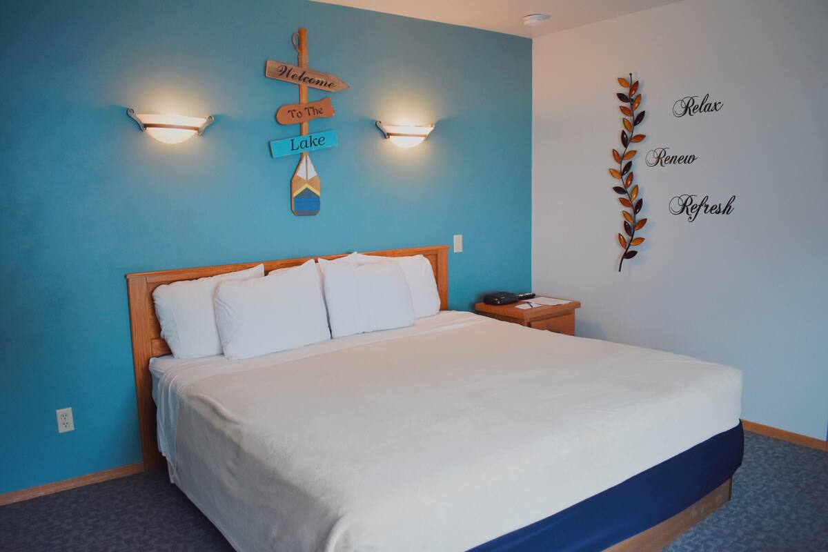 Un dormitorio con cama, mesita de noche, un letrero en la pared y un adorno mural.