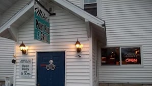 A building with a sign reading 'Mike's PORT PUB & GRILL,' a blue door, and two wall-mounted lights. - Innlet Motel (Sturgeon Bay)