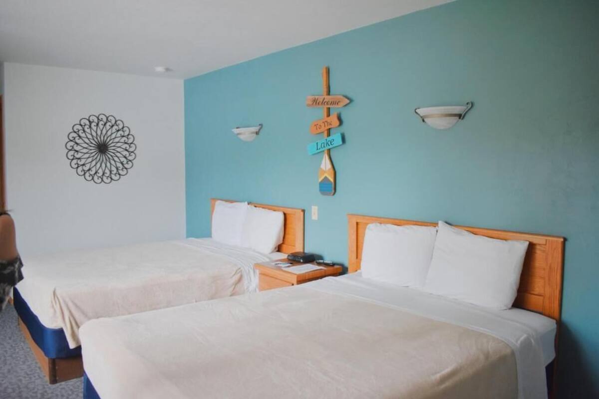 Una habitación de hotel con dos camas, un cartel decorativo y una obra de arte en la pared.