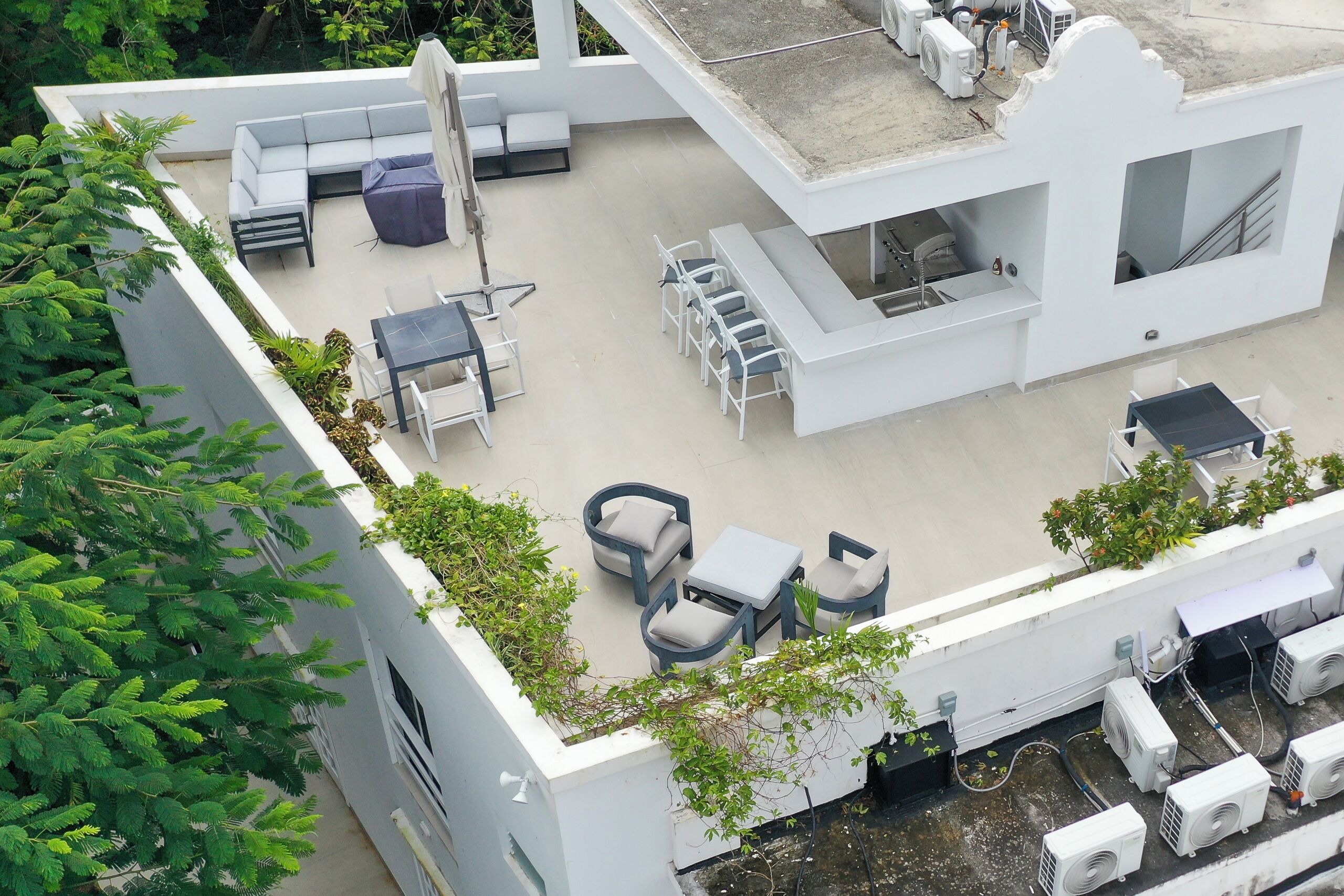 A rooftop patio with outdoor seating, air conditioning units, and a staircase.