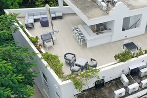 Eine Dachterrasse mit Sitzgelegenheiten im Freien, Klimaanlagen und einer Treppe.