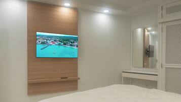A bedroom with a TV mounted on the wall, a bed, a bedside table, and a mirror.
