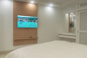 Ein Schlafzimmer mit an der Wand montiertem Fernseher, einem Bett, einem Nachttisch und einem Spiegel.