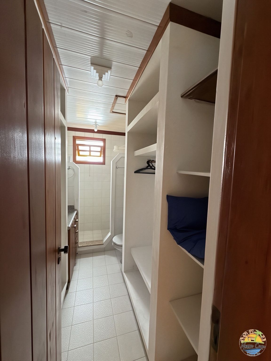 Un pasillo estrecho con ducha, inodoro y cama con colchón azul.