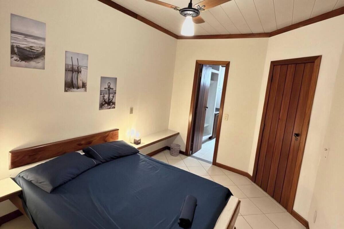 Un dormitorio con una cama, un ventilador de techo y tres cuadros colgados en la pared.