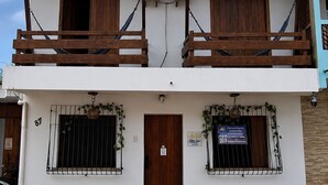 A two-story building with a balcony, a wooden door, and a window with a metal grill. - Nossa Casa Itacaré (Itacaré)