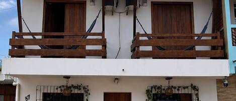 Ein zweistöckiges Gebäude mit Balkon, Holztür und Fenster mit Metallgitter.