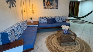 A living room with a sofa set, a coffee table, a ceiling fan, and a wall-mounted light fixture. - Nossa Casa Itacaré (Itacaré)