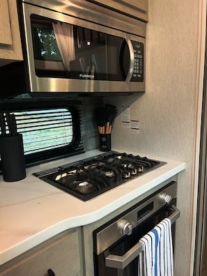 Une cuisine équipée d’un four à micro-ondes, d’une cuisinière et d’un four, le tout en acier inoxydable.