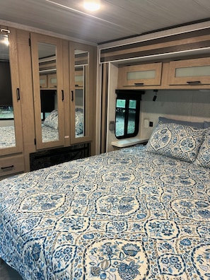 Une chambre à coucher avec une couvre-lit à motifs, des armoires en bois et une fenêtre.