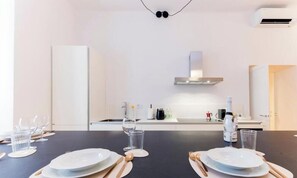 A modern kitchen with a central island, white cabinetry, and a stainless steel range hood. - Train Station| 3BR| A/C| City Center By Tilo (Genova)