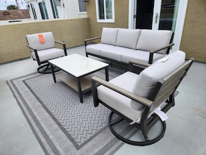 Eine Terrasse mit einer Sofagarnitur, Stühlen und einem kleinen Tisch.