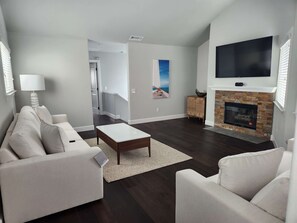 Ein Wohnzimmer mit Sofa, Couchtisch, Kamin, Fernseher und Kunstwerken an der Wand.