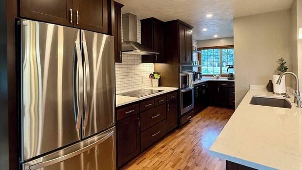 A modern kitchen with dark wooden cabinets, stainless steel appliances, and a wooden floor. - Spacious 4-bed in Eugene - Gated, Fenced Estate 10 min from Downtown/Wineries (Eugene)