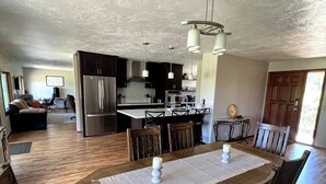 A spacious kitchen with a central island, wooden dining table, and chairs. - Spacious 4-bed in Eugene - Gated, Fenced Estate 10 min from Downtown/Wineries (Eugene)