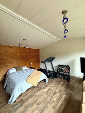 A bedroom with a bed, exercise equipment, and a TV. - Spacious 4-bed in Eugene - Gated, Fenced Estate 10 min from Downtown/Wineries (Eugene)