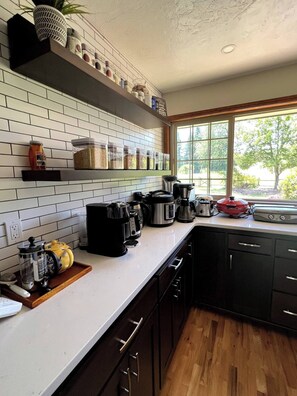 A kitchen with white subway tiles, black cabinets, and a window with a view of greenery. - Spacious 4-bed in Eugene - Gated, Fenced Estate 10 min from Downtown/Wineries (Eugene)