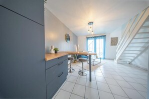 A modern kitchen with a wooden countertop, bar stools, and a staircase leading to an upper level. - T2 moderne et chaleureux en centre-ville (Lorient)