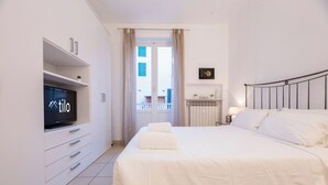 Ett hotellrum med en säng, en tv, en garderob, ett element och utsikt över omgivningarna.