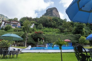 A garden with outdoor seating, a pool, and a mountain backdrop. - Hotel Bungalows Andrea (Tepoztlan)