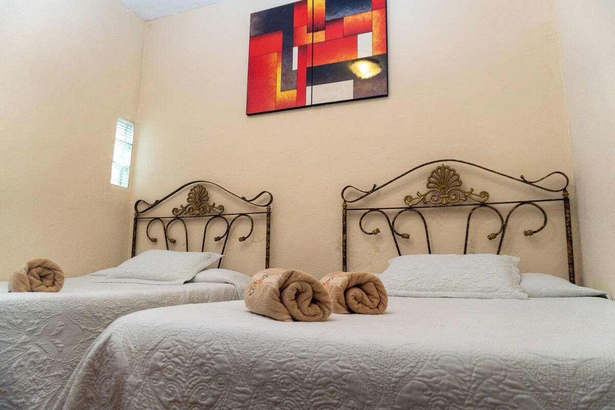 Habitación de hotel con dos camas, un cuadro decorativo en la pared y una ventana.