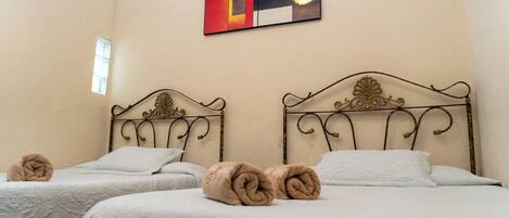 A hotel room with two beds, a decorative wall painting, and a window.