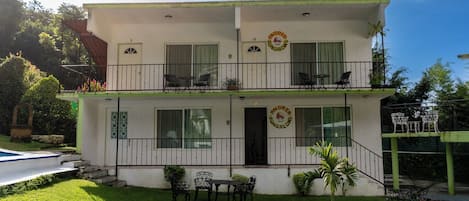 A two-story building with balconies, a swimming pool, and outdoor seating.