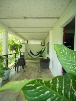 A covered outdoor area with a hammock, chairs, and potted plants. - La Veranda & Restaurant  (Minca)