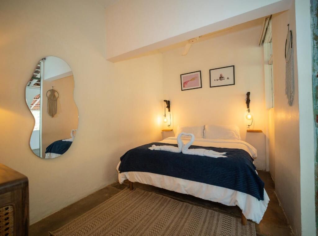 Un dormitorio con cama, un espejo, dos lámparas de pared y una alfombra.