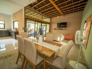Un comedor con una mesa de madera, sillas y un televisor montado en la pared.