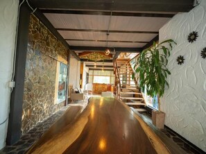 Un pasillo con suelo de madera, pared de piedra, escalera y una planta en maceta.