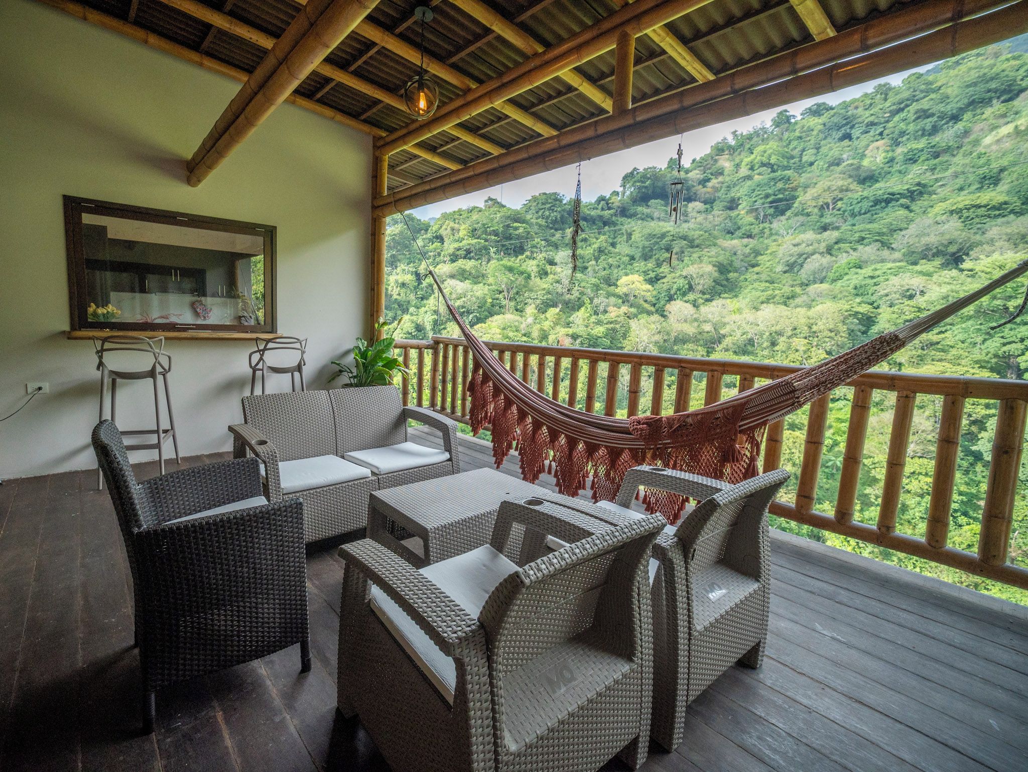 A covered outdoor seating area with wicker furniture and a hammock.