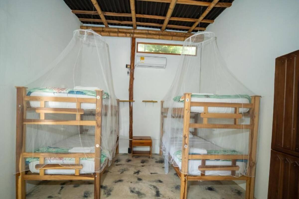 Dues lliteres de fusta amb mosquiteres, un tamboret petit de fusta i un armari de fusta.
