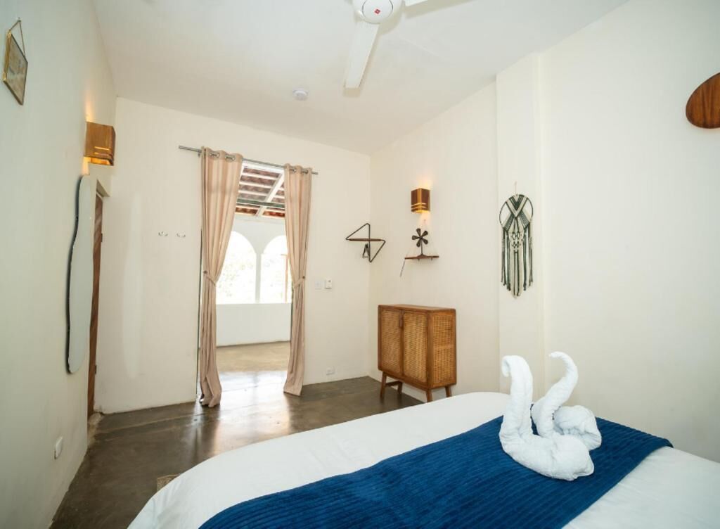 Un dormitorio con una cama, un armario de madera, una lámpara de pared y una puerta que da a otra habitación.