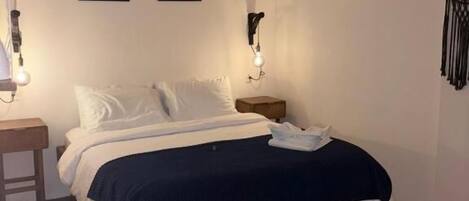 Una camera da letto con un letto, un comodino, una lampada a parete e due quadri appesi.