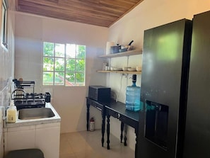 A compact kitchen with a sink, a stove, a water dispenser, and a refrigerator. - La Veranda & Restaurant  (Minca)