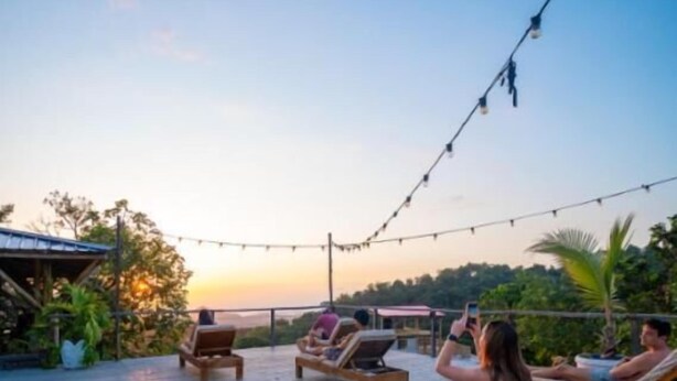 A wooden deck with lounge chairs and a string of lights.