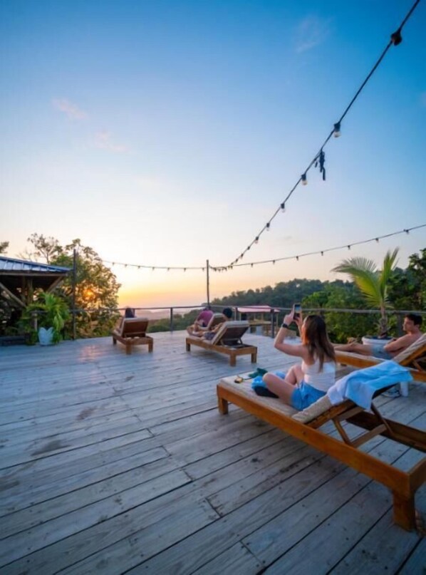 Una terraza de madera con sillones de descanso y luces colgantes.