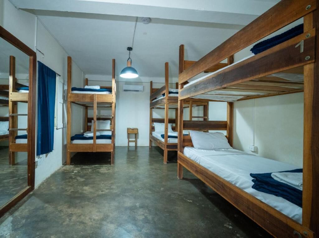 Un dormitorio con literas, una mesita, una silla y una lámpara colgante.