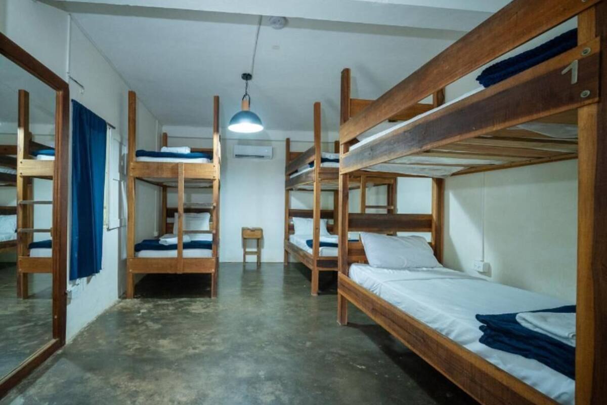 Una habitació de dormitori amb literes, una taula petita, una cadira i una làmpada penjant.