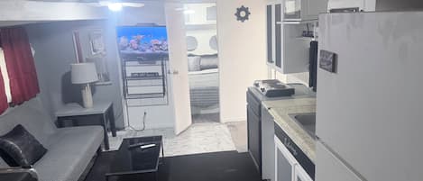 Um espaço compacto com cozinha compacta, um sofá, uma mesa de centro e uma televisão.